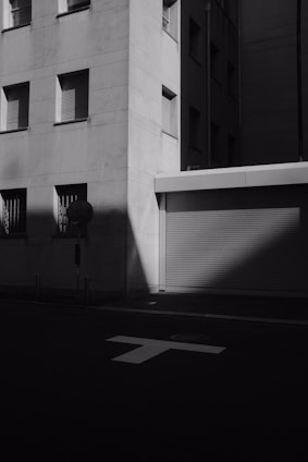A black and white photograph capturing an empty urban corner with subtle shadows and textures, evoking silence and memory.