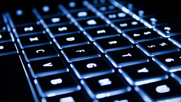 A close-up of fingers swiftly typing on a sleek keyboard with highlighted keys.
