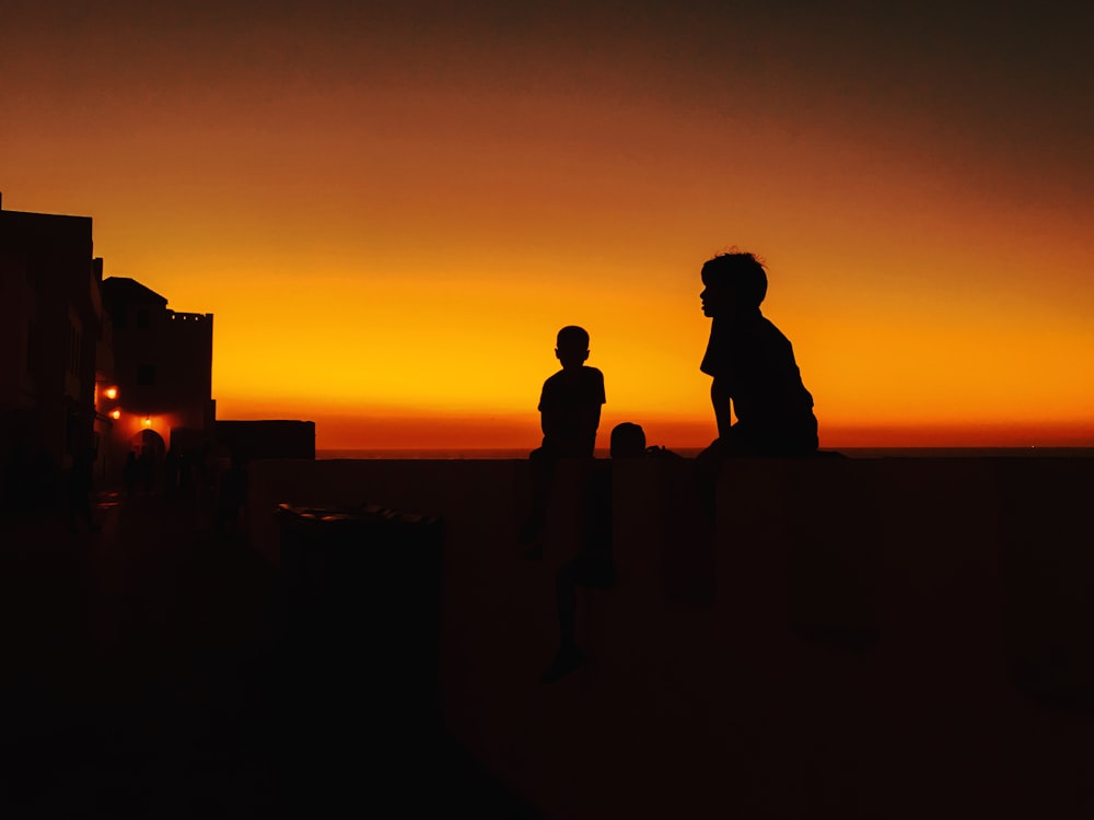 Silueta de 2 personas de pie en la roca durante la puesta del sol