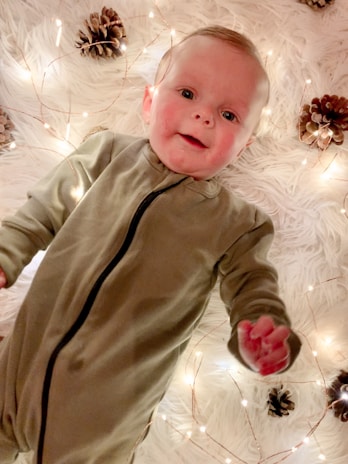 Smiling Indian baby wearing a soft teal mightwee diaper, sitting among cozy fairy lights.