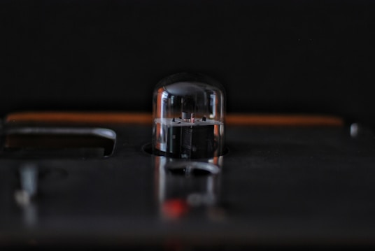 A close-up view of a vacuum tube on a dark surface with a soft focus background, creating a sleek and industrial aesthetic.