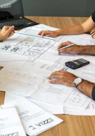 people reviewing architectural blueprints on desk
