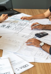 people reviewing architectural blueprints on desk