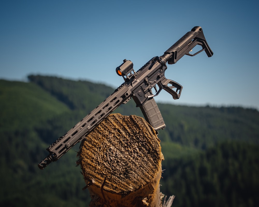 schwarzes Sturmgewehr auf braunem Holzstamm