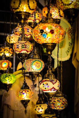 A collection of decorative hanging mosaic lamps with intricate designs and vibrant colors, illuminated warmly against a dim background, creating an inviting ambiance.