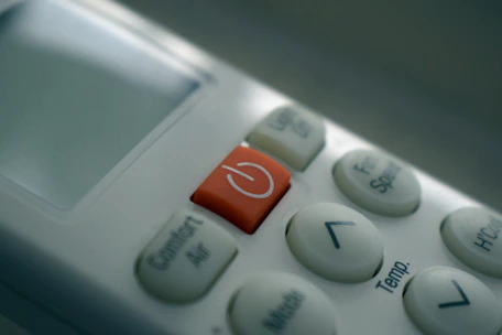 Close-up of a sleek air conditioning remote control with temperature settings.