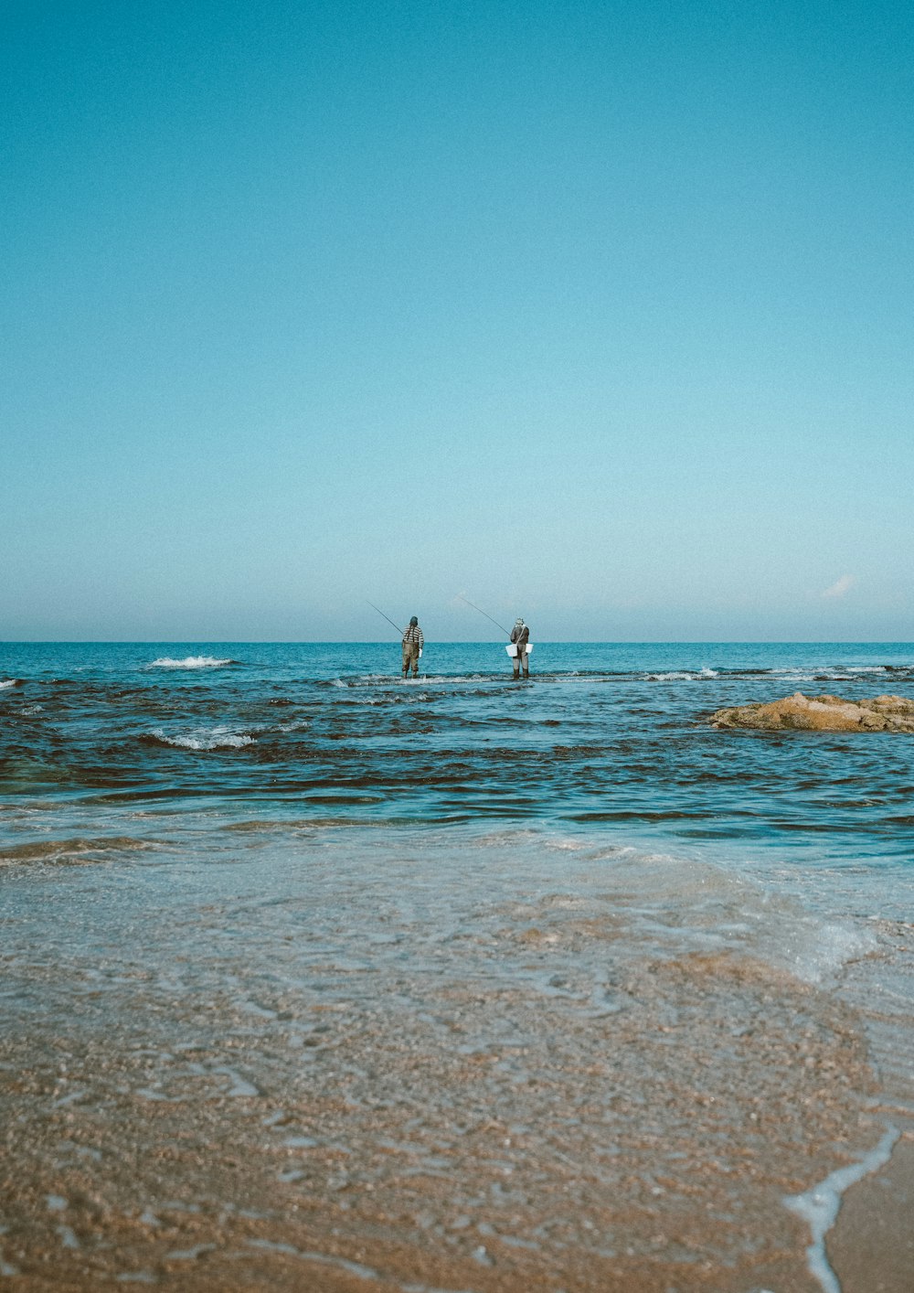 2 people standing on beach during daytime