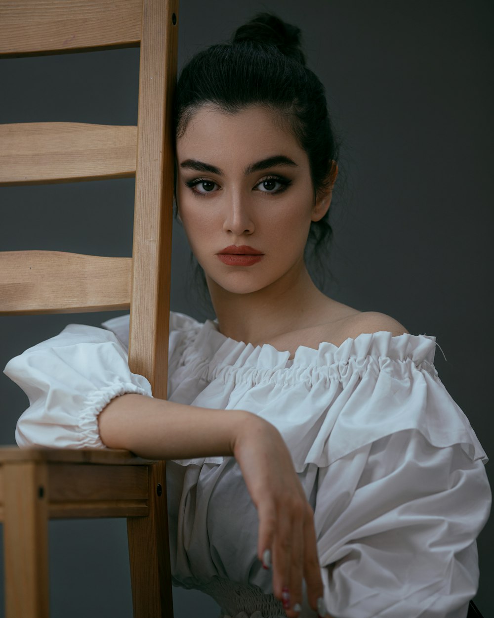 femme en robe blanche assise sur une chaise en bois marron