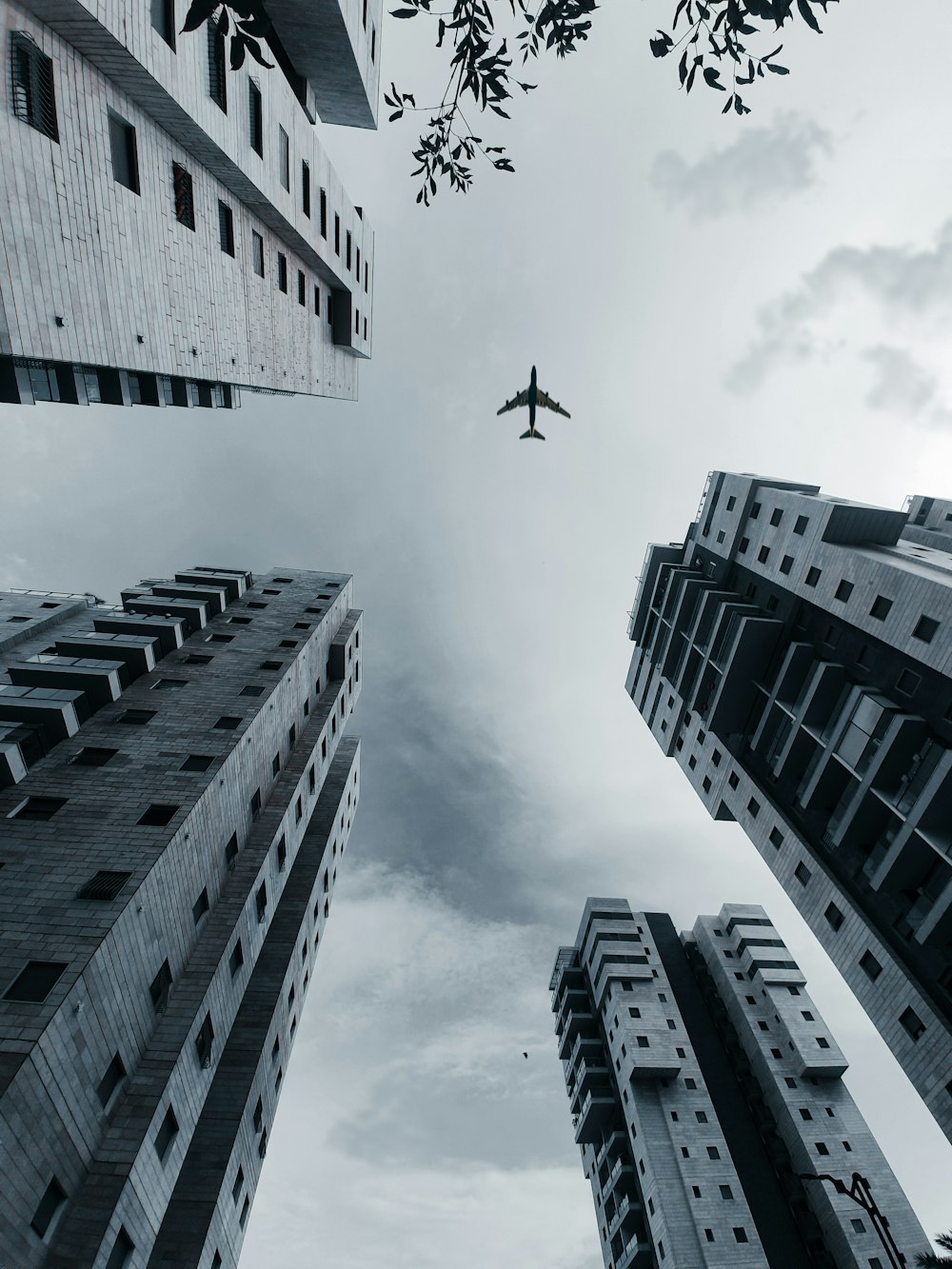 airplane flying over high rise buildings during daytime