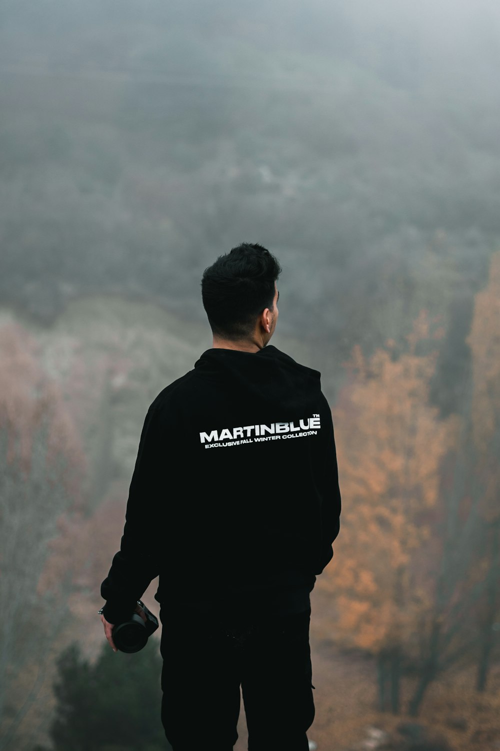 man in black and white adidas hoodie standing on brown field