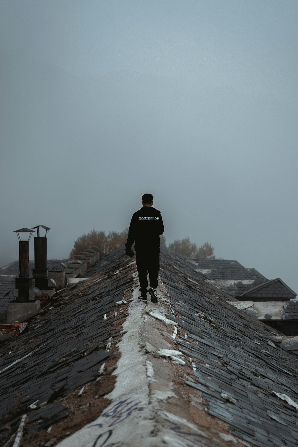 man in black jacket walking on gray concrete pathway during daytime