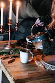 A cozy scene with a teapot pouring warm ginger tea into a ceramic cup