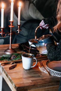 A serene morning scene with a person gently pouring warm herbal tea into a cup beside a small bowl of fresh turmeric and ginger.