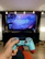 A satisfied gamer showing off his new PlayStation 5 in a vibrant room filled with gaming posters.