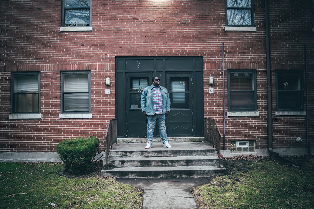 man in blue jacket standing on gray concrete stairs