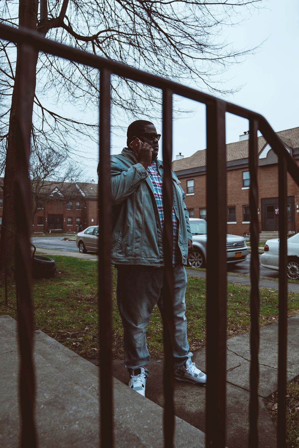 man in blue denim jeans standing near brown wooden fence during daytime