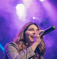 woman in white and black plaid shirt holding microphone