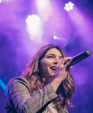 woman in white and black plaid shirt holding microphone