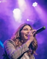 woman in white and black plaid shirt holding microphone