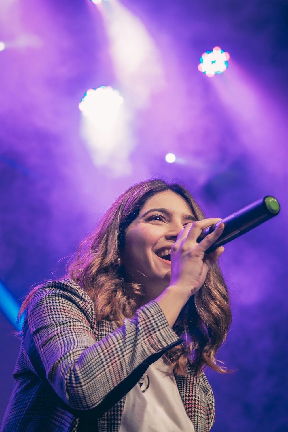 woman in white and black plaid shirt holding microphone