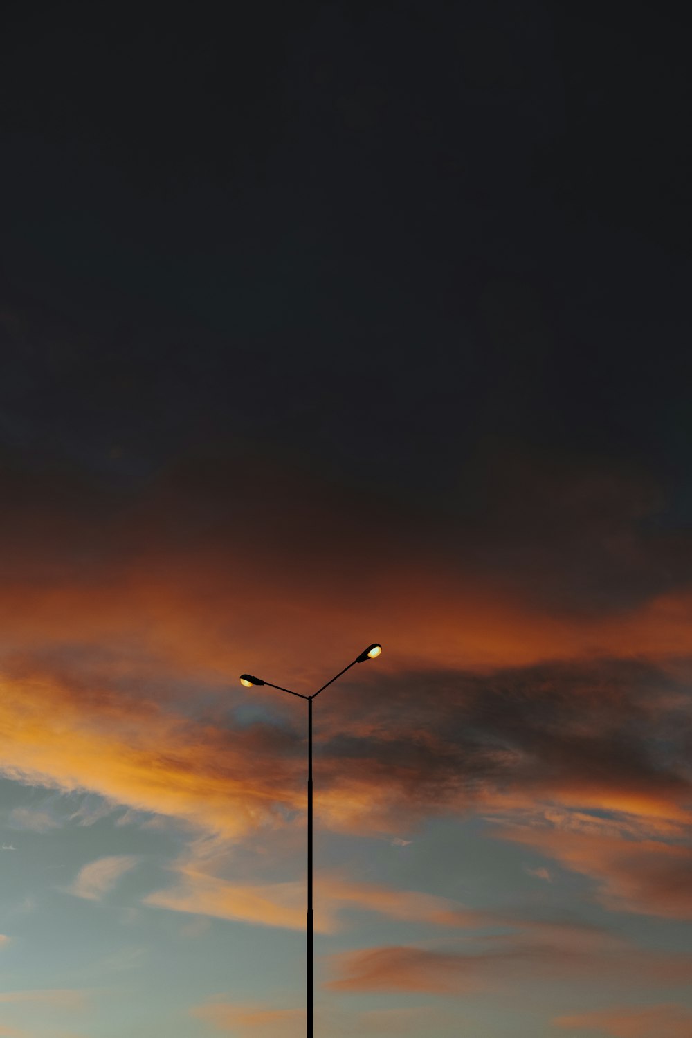 farola negra bajo cielo naranja y azul