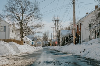 A quiet Somerville street with cleared sidewalks and snow piled neatly to the sides.