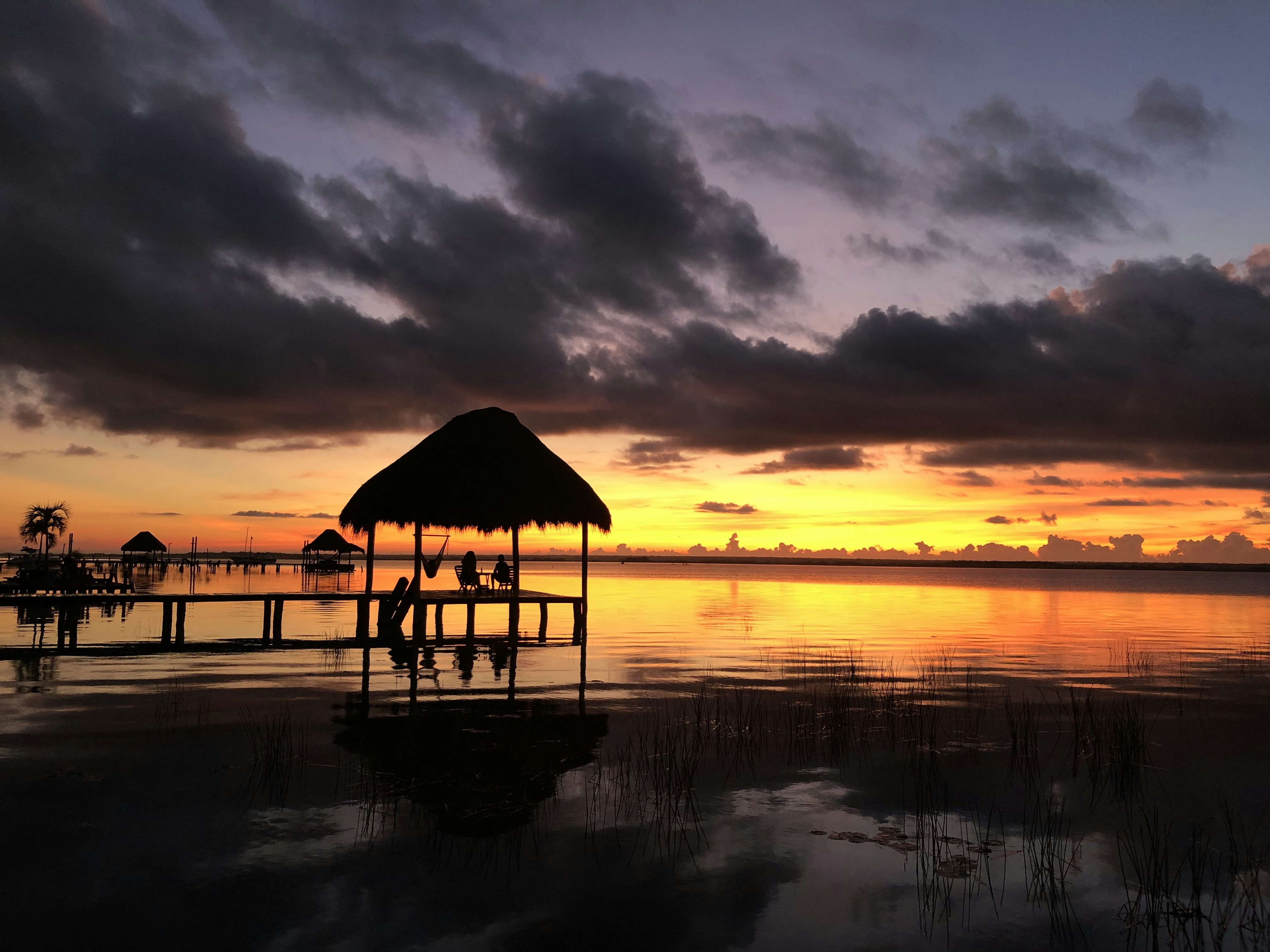 brown wooden beach house on body of water during sunset, 