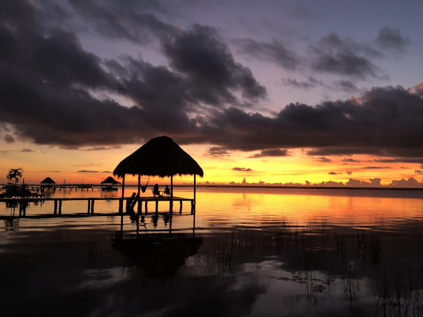 A serene sunset over the turquoise waters of the Maldives, with a couple enjoying the view.