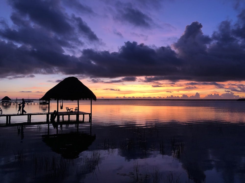 silhouette of gazebo on water during sunset