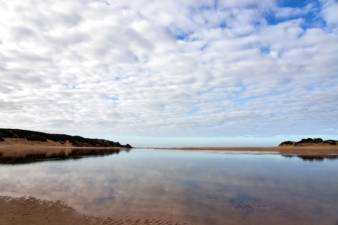 body of water under white clouds and blue sky during daytime