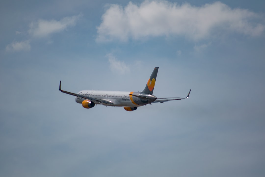 white and yellow airplane flying under blue sky during daytime