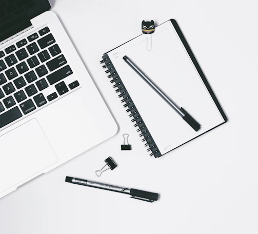 Minimalist workspace featuring a modern notebook, black pen, and subtle gold-accented decor.