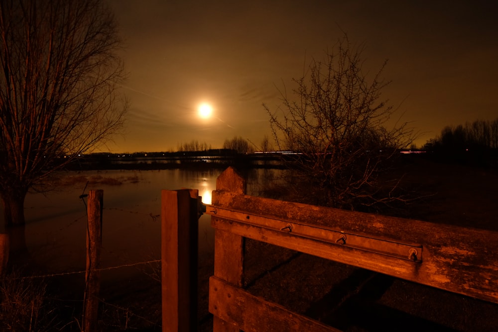 brown wooden bench near body of water during night time