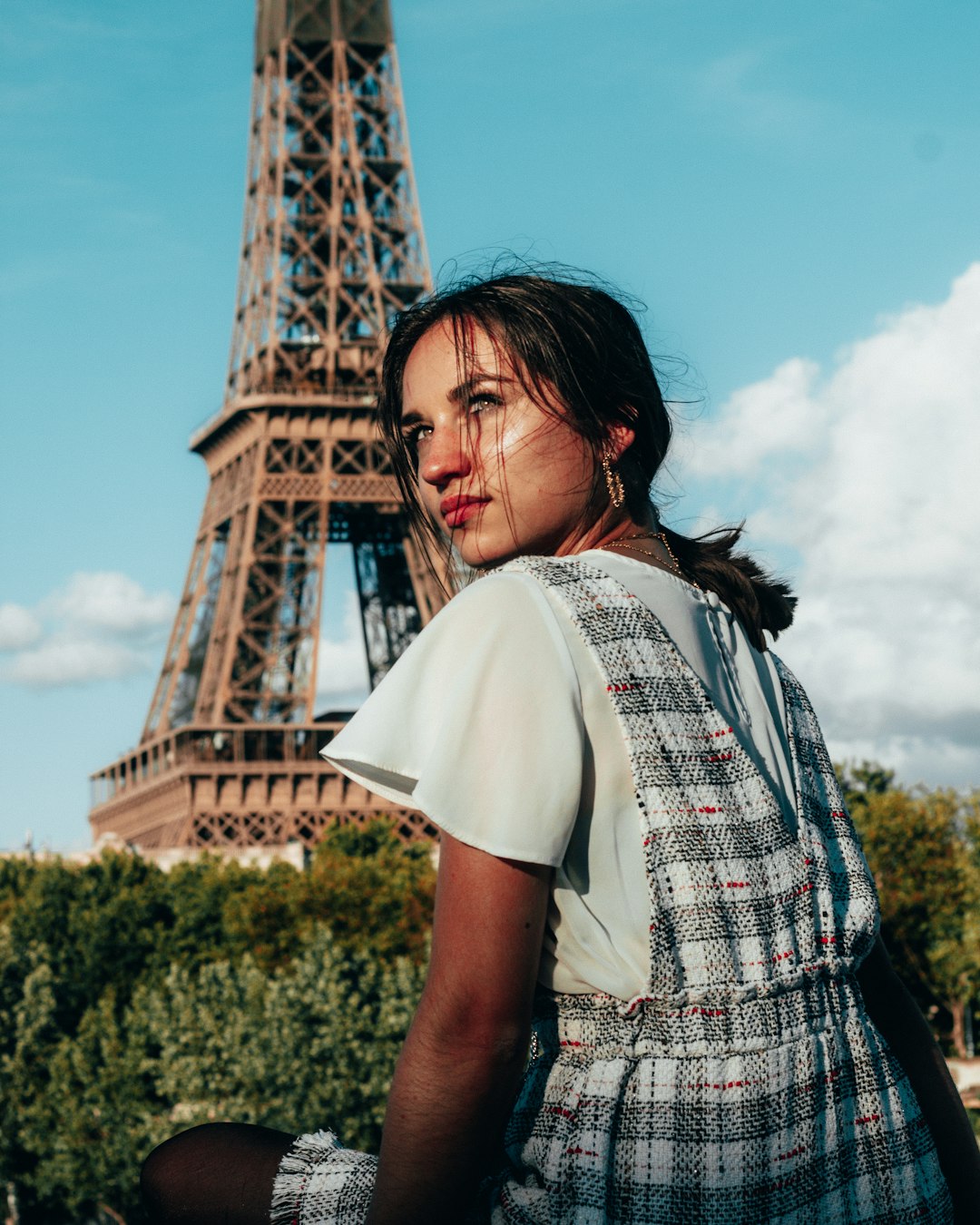 woman in white and black plaid shirt standing near eiffel tower during daytime