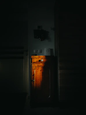 A freshly painted dark cabinet glowing under warm workshop lights.