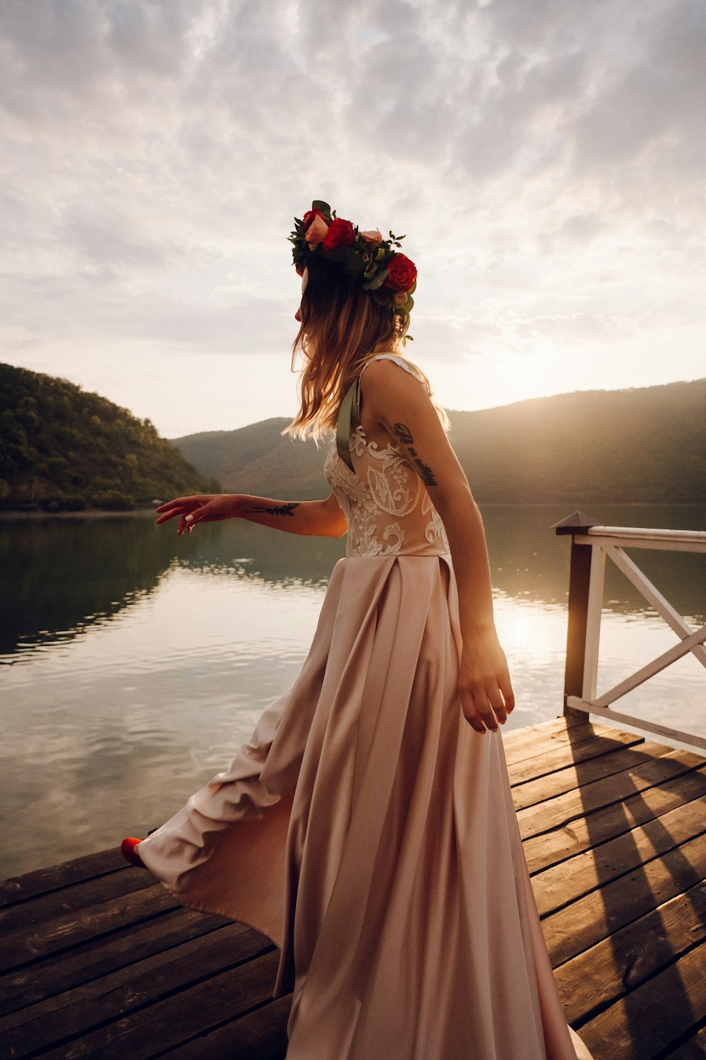 Mujer en vestido rosa de pie en muelle de madera durante el día