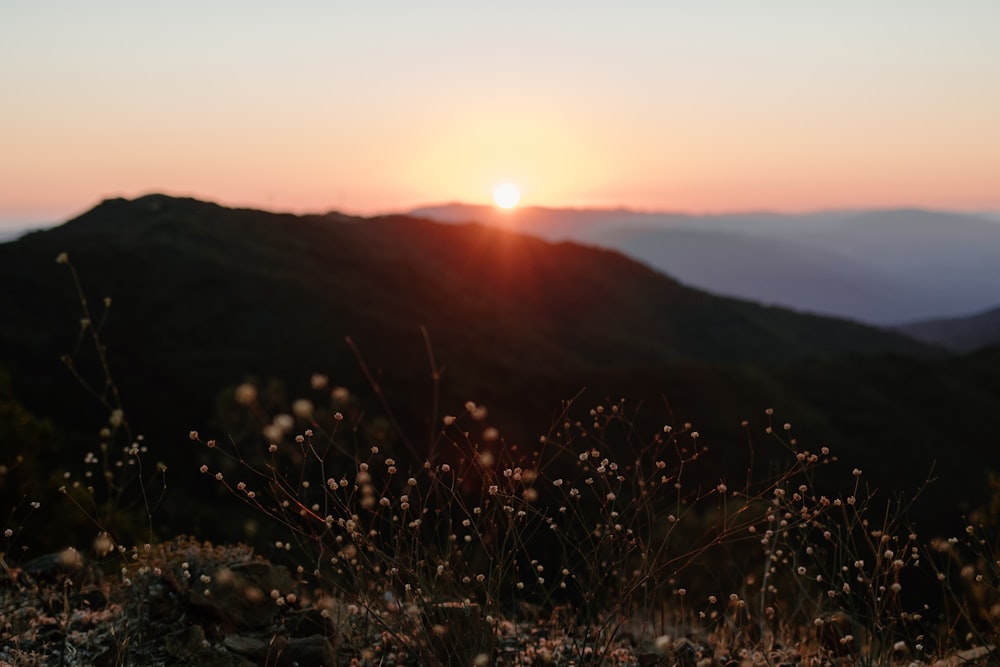 the sun is setting over a mountain range