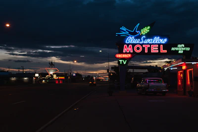 Neon and LED signs illuminating a storefront at dusk.