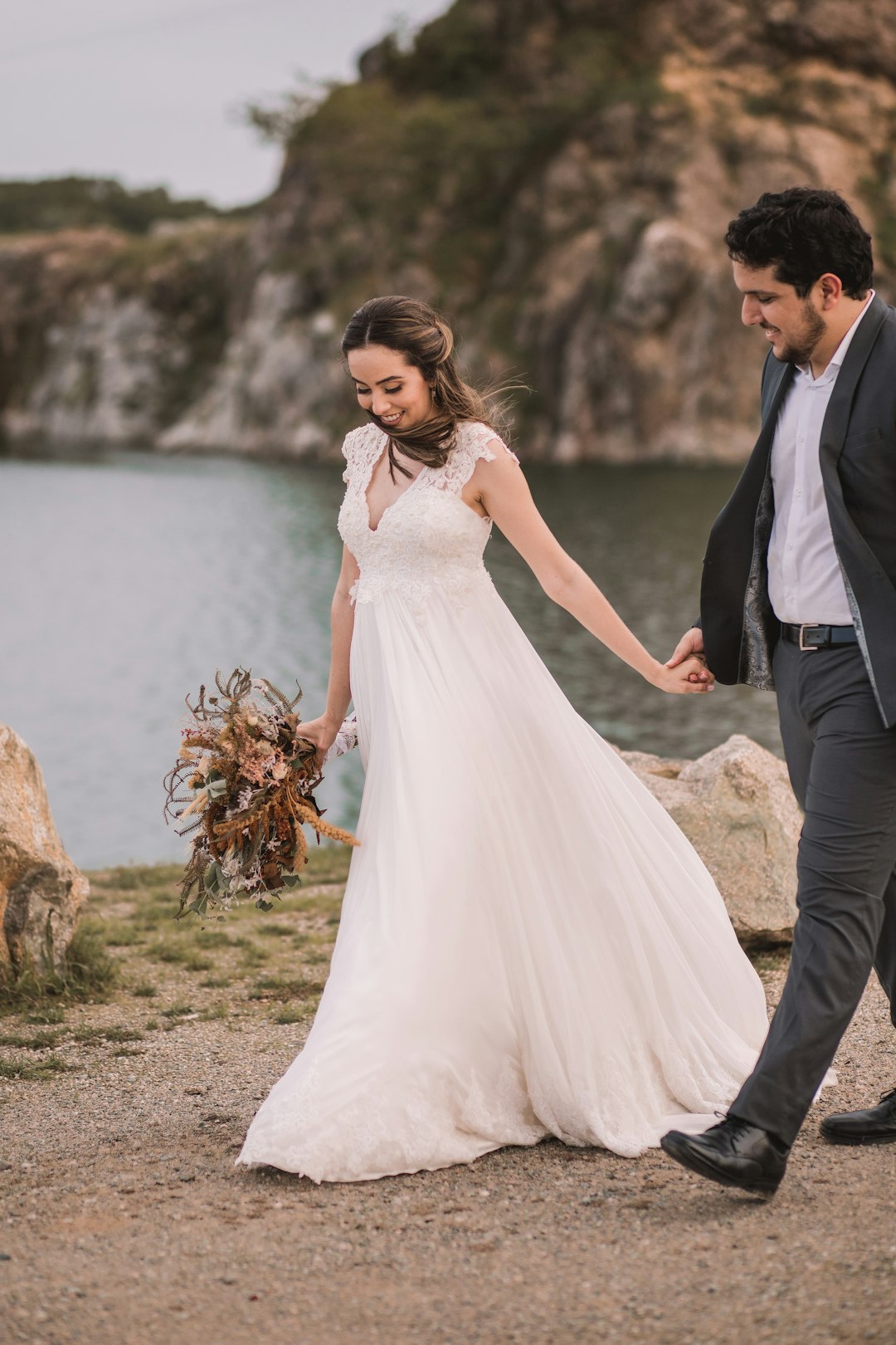 man in black suit and woman in white wedding dress standing on brown grass field during