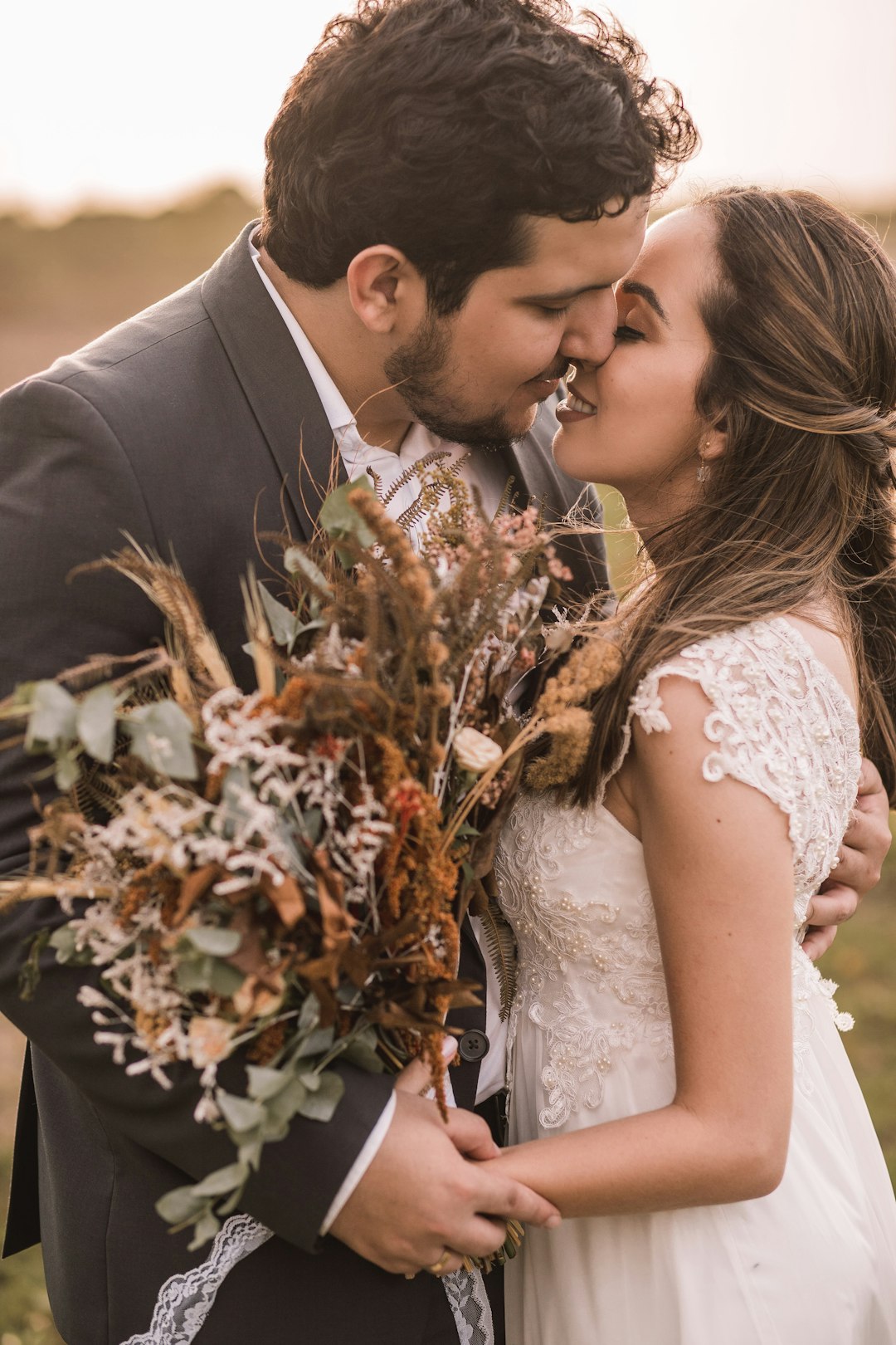 man in black suit jacket kissing woman in white floral wedding dress