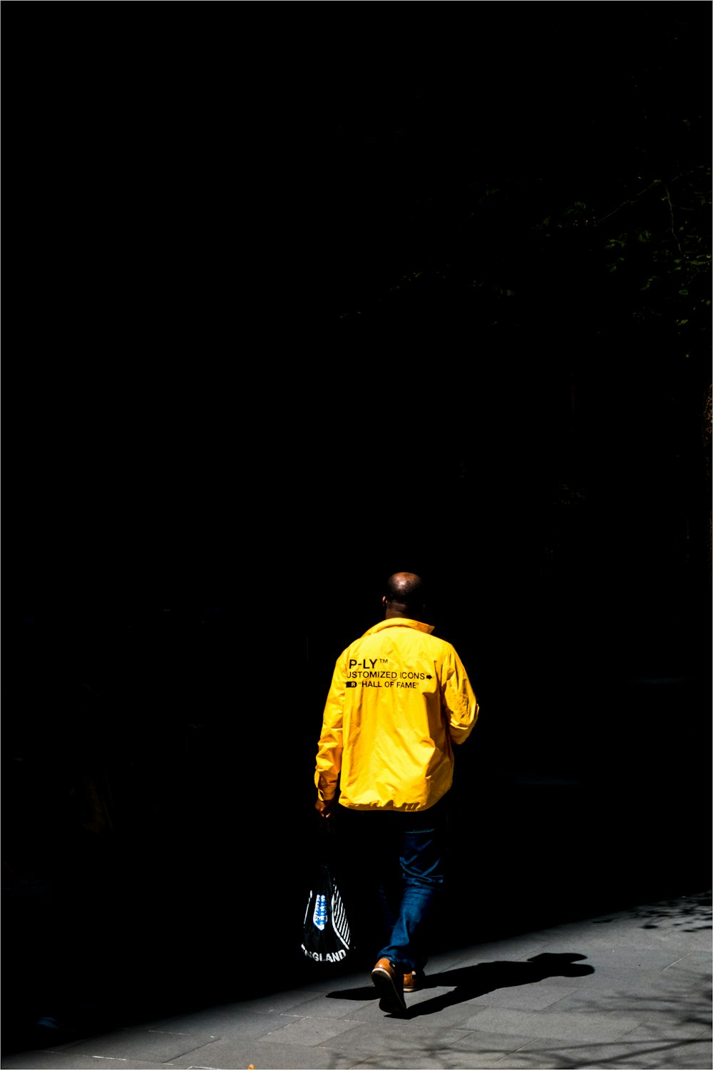 a man in a yellow jacket walking down a street