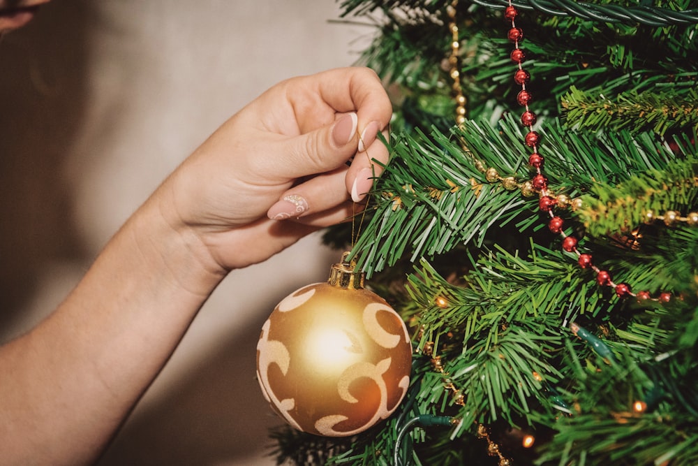 person holding gold and white bauble