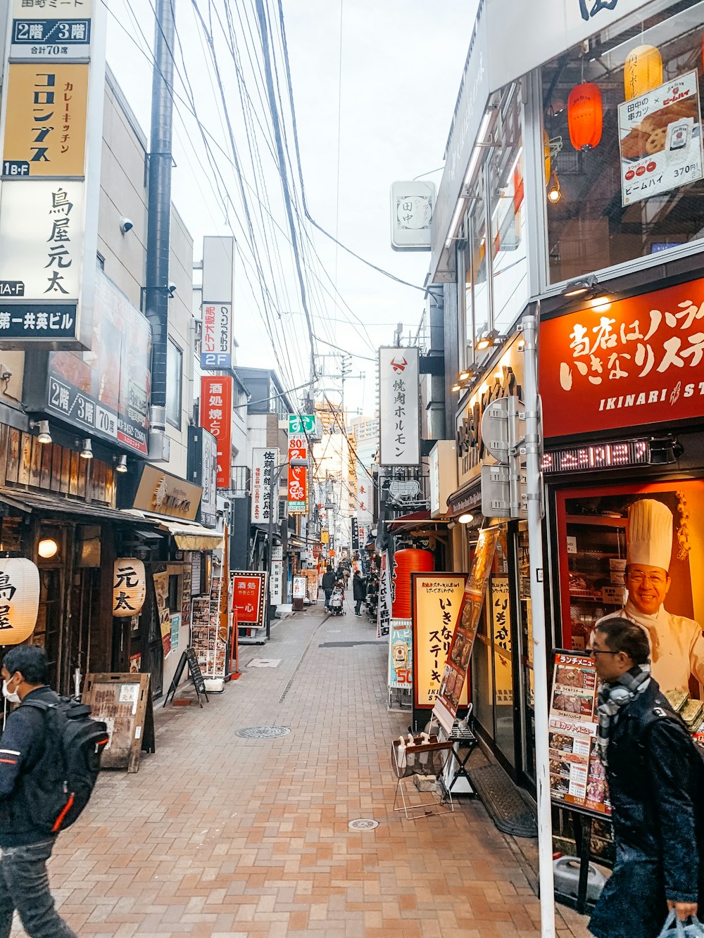 man in black jacket walking on sidewalk during daytime