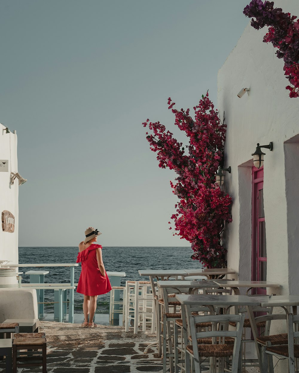 woman in red dress standing on brown wooden stairs near body of water during daytime