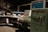 A vintage computer room featuring large, retro computers and control panels with numerous buttons and switches. The room includes a UNIVAC 1232 machine and several other large computing devices, arranged in a dimly lit space that emphasizes their mechanical and industrial design.