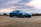 A sleek car parked on a coastal road with a clear blue sky in the background.