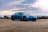 A sleek car parked on a coastal road with a clear blue sky in the background.