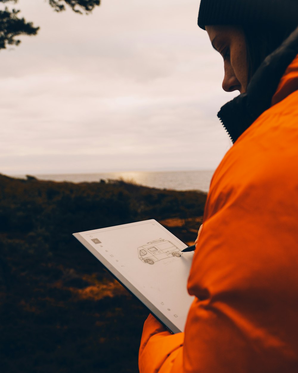 man in orange hoodie reading book