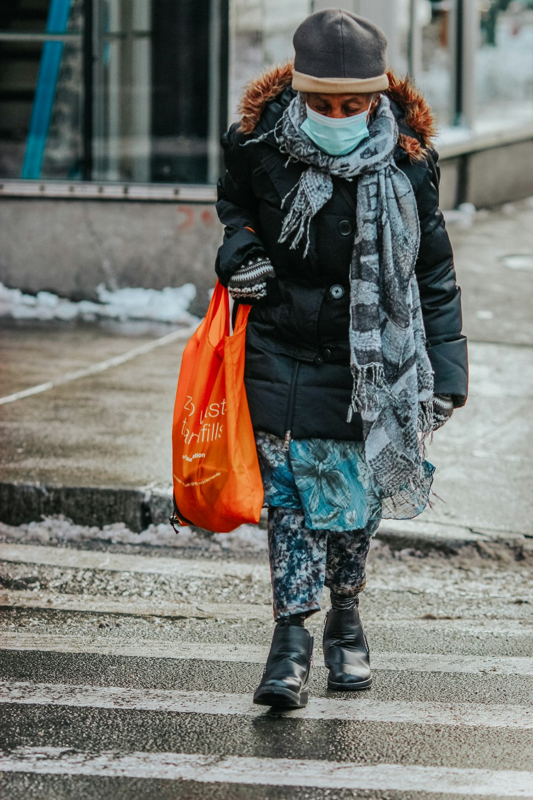 woman in black and white jacket holding orange plastic bag