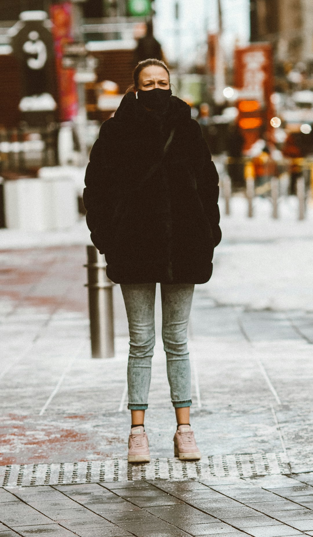 person in black coat and blue denim jeans walking on sidewalk during daytime